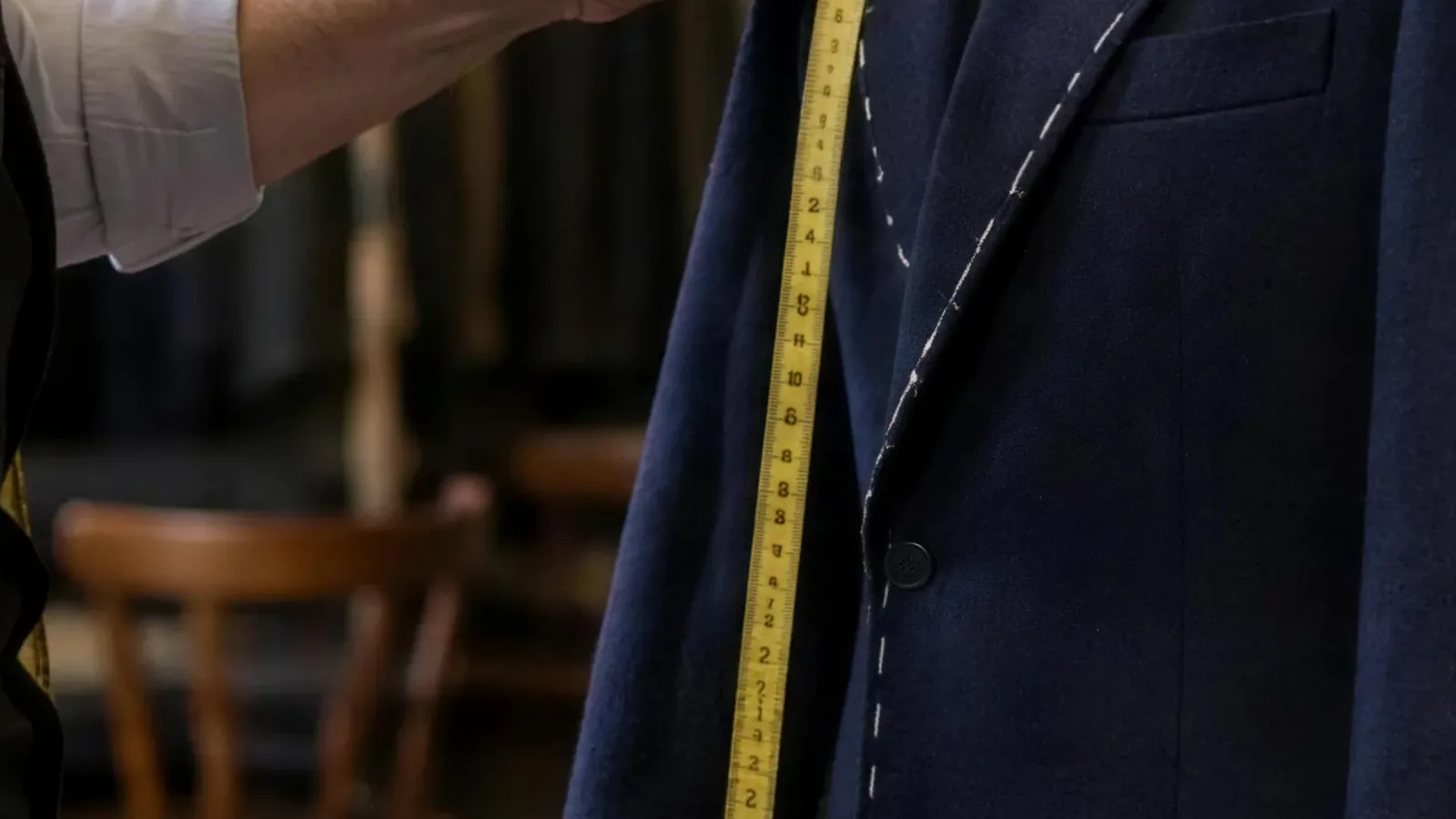 The macro of the tape on the lapel, the tailor's hand entering
